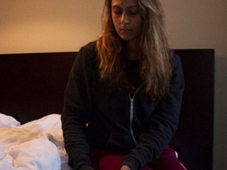 Woman testing her blood sugar in bed at night