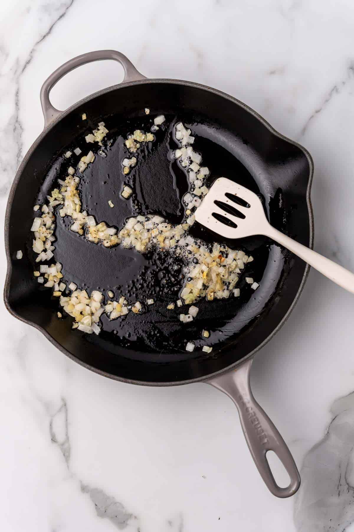 Oil, onion, garlic, and seasoning sautéing in a pan