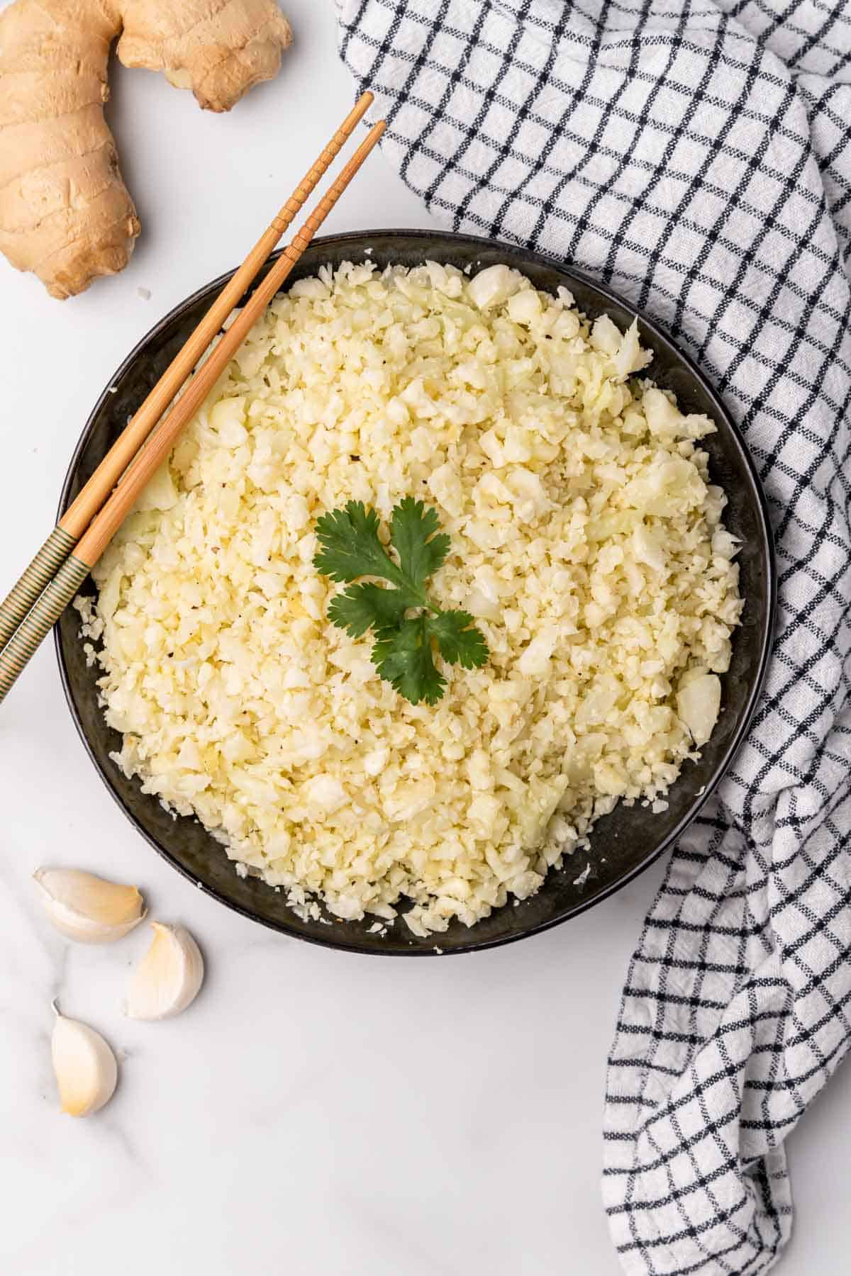 Bowl of cauliflower rice on table with chopsticks