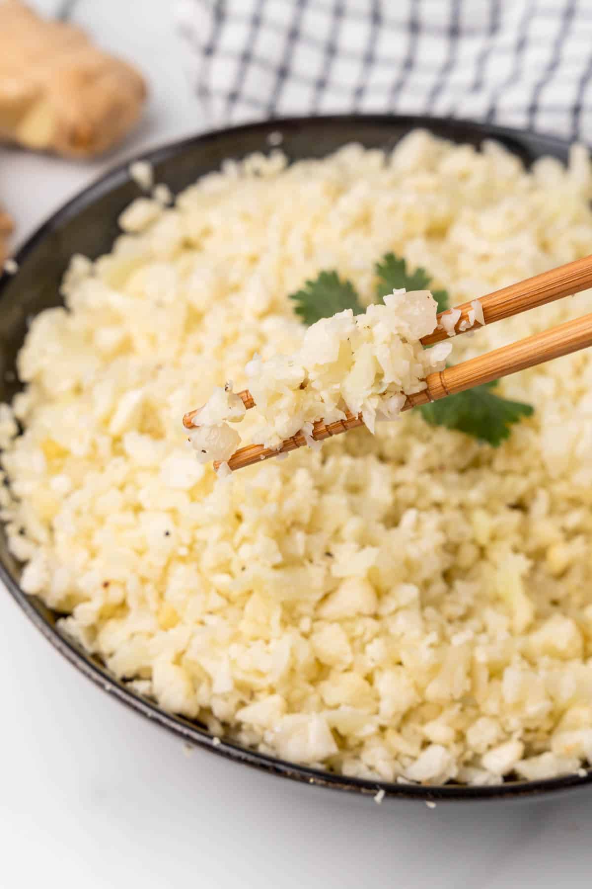 Pair of chopsticks lifting rice from a bowl