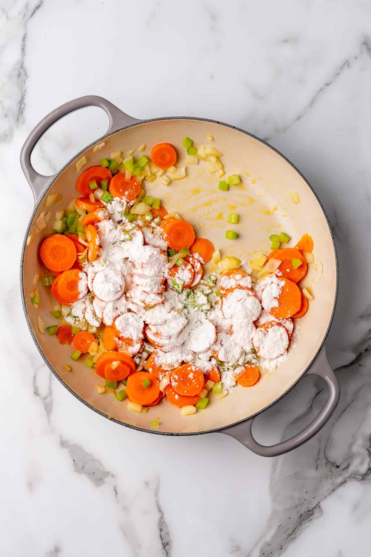 Flour sprinkled over the vegetables in the pan