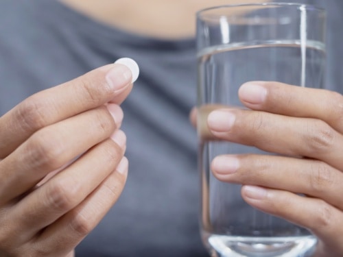Person holding metformin pill and glass of water