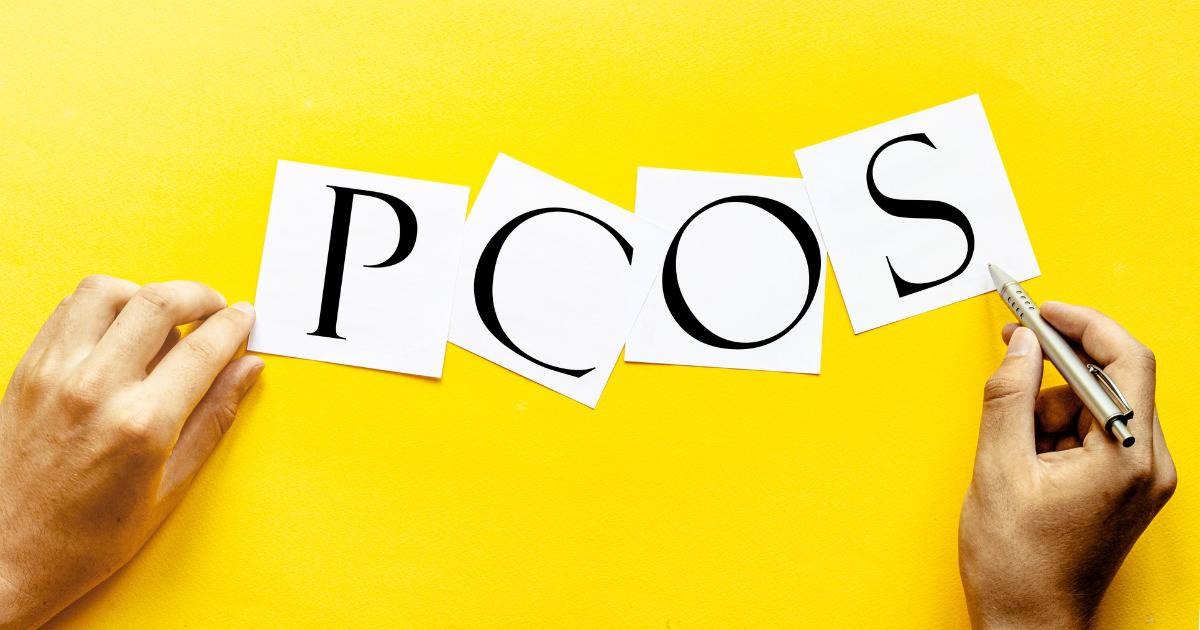 Hand writing the letters "PCOS" on a piece of paper