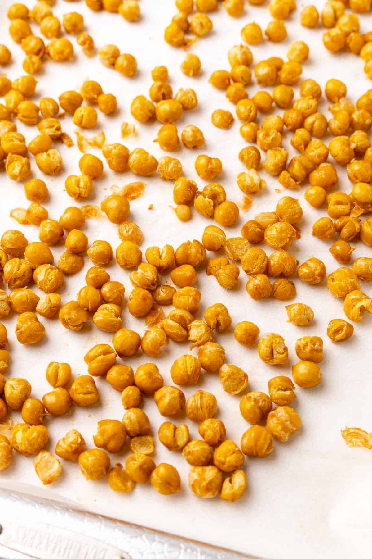 Closeup of roasted chickpeas on a baking sheet lined with parchment paper