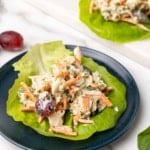 Closeup of chicken salad on a lettuce leaf on a small navy plate on a white marble background
