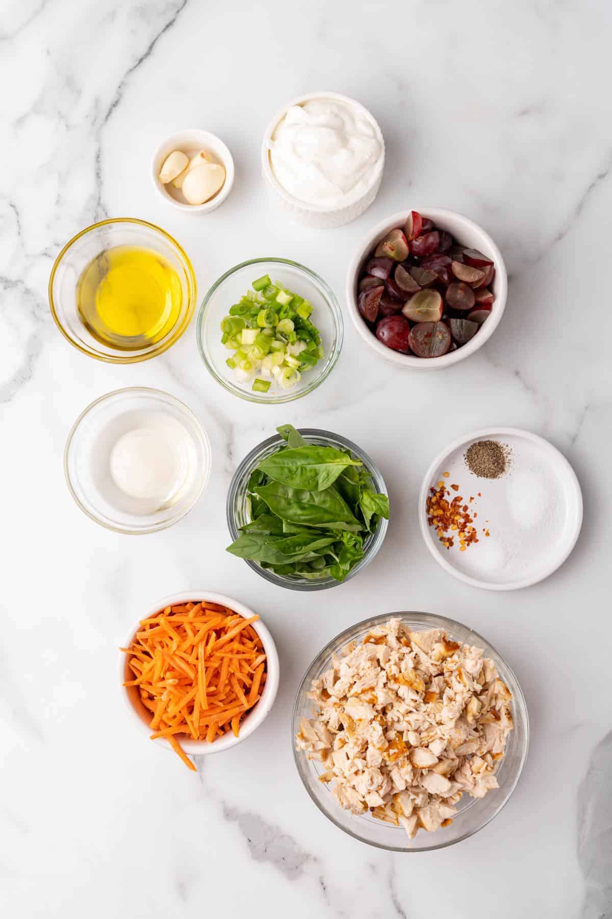 Ingredients for recipe separated into individual bowls and ramekins on a white marble surface, as seen from above