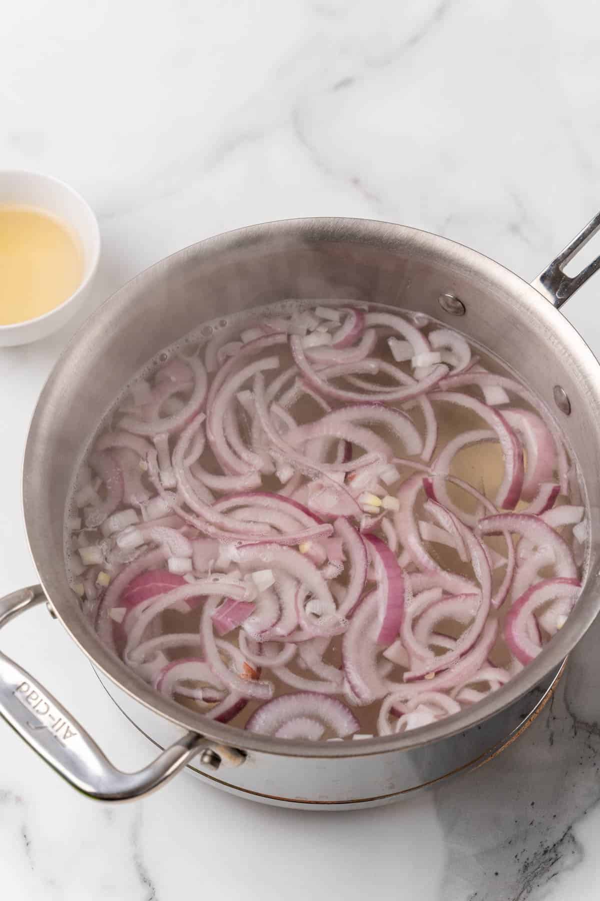 Sliced onions boiled in a metal pot full of water