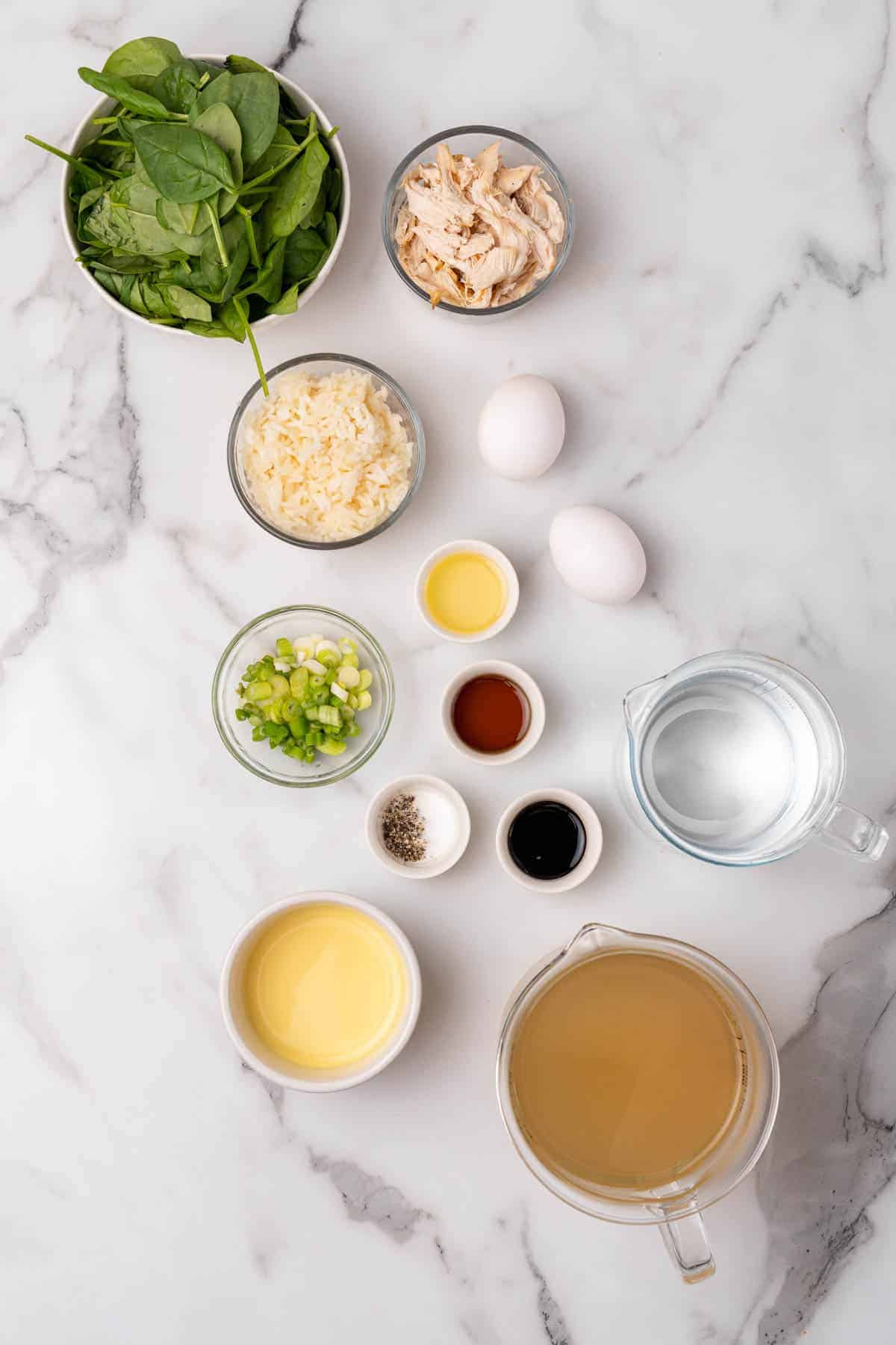 Ingredients for recipe separated into individual bowls and ramekins, as seen from above on a white marble surface