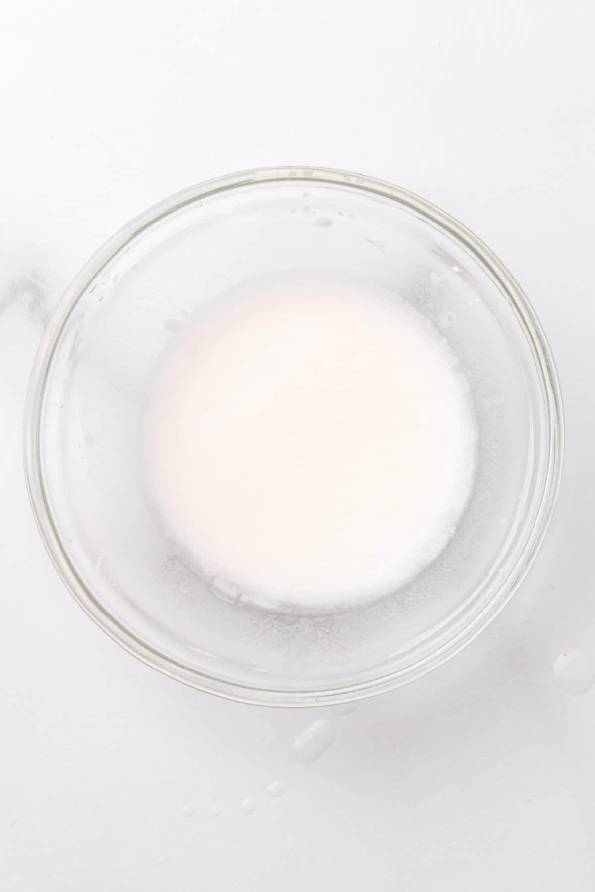 Cornstarch paste in a glass bowl on a white surface, as seen from above