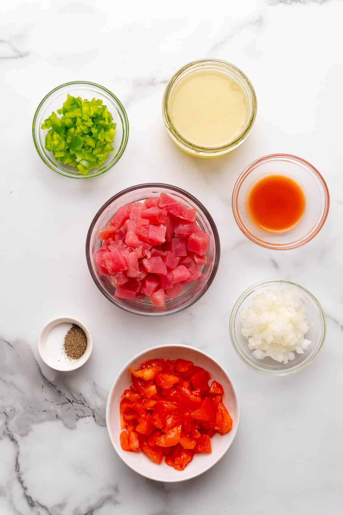 Ingredients for recipe separated into individual ramekins and bowls, as seen from above on a white background