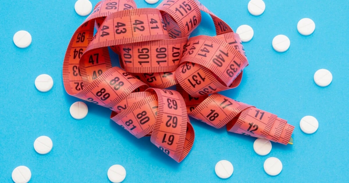 A measuring tape and pills lying on a table