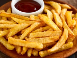 Plate covered in french fries and a small cup of ketchup