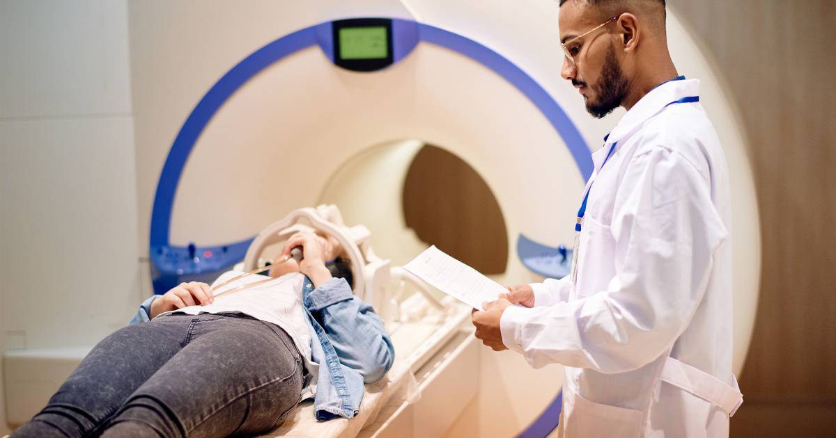 Doctor stands next to patient in an MRI device