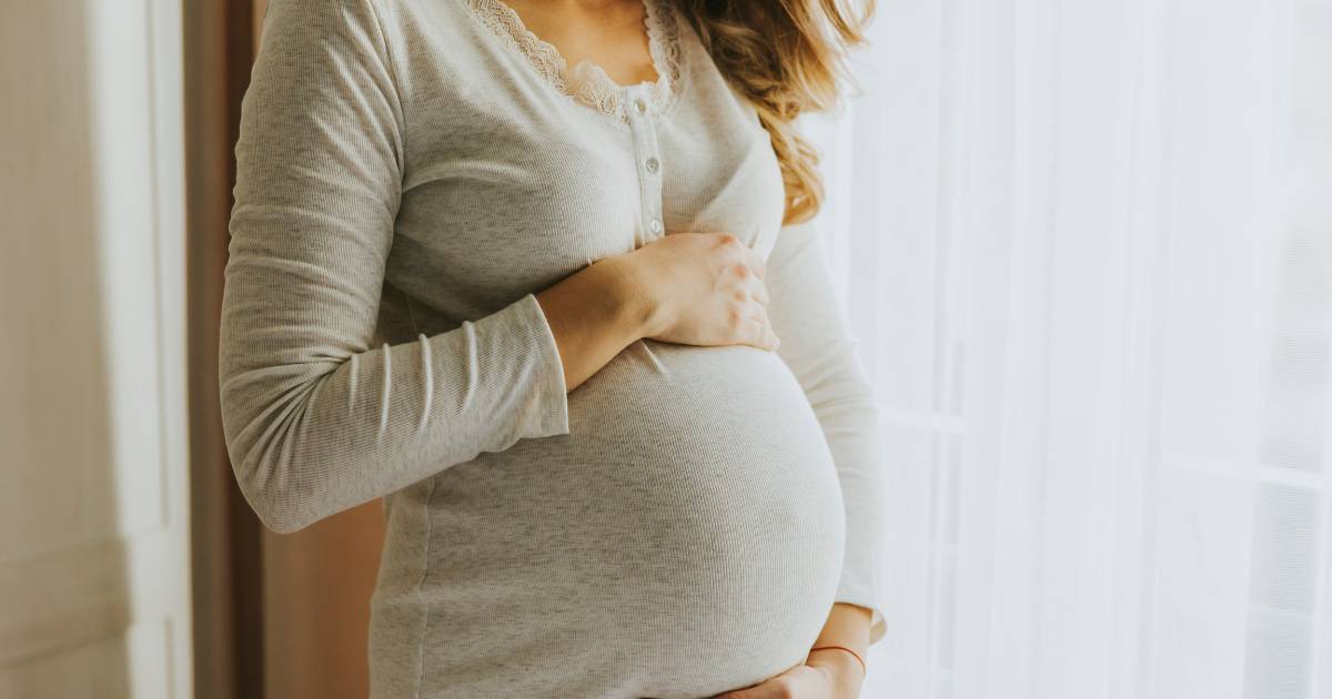 Pregnant woman cradles her stomach