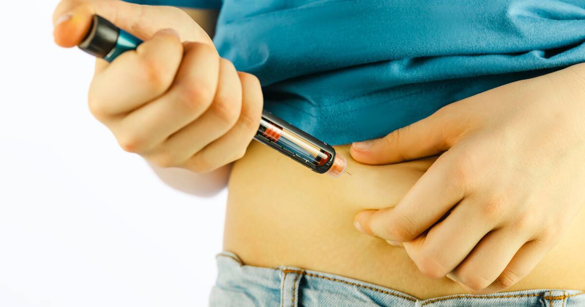 Image of person injecting a pen into their abdomen