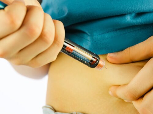Image of person injecting a pen into their abdomen