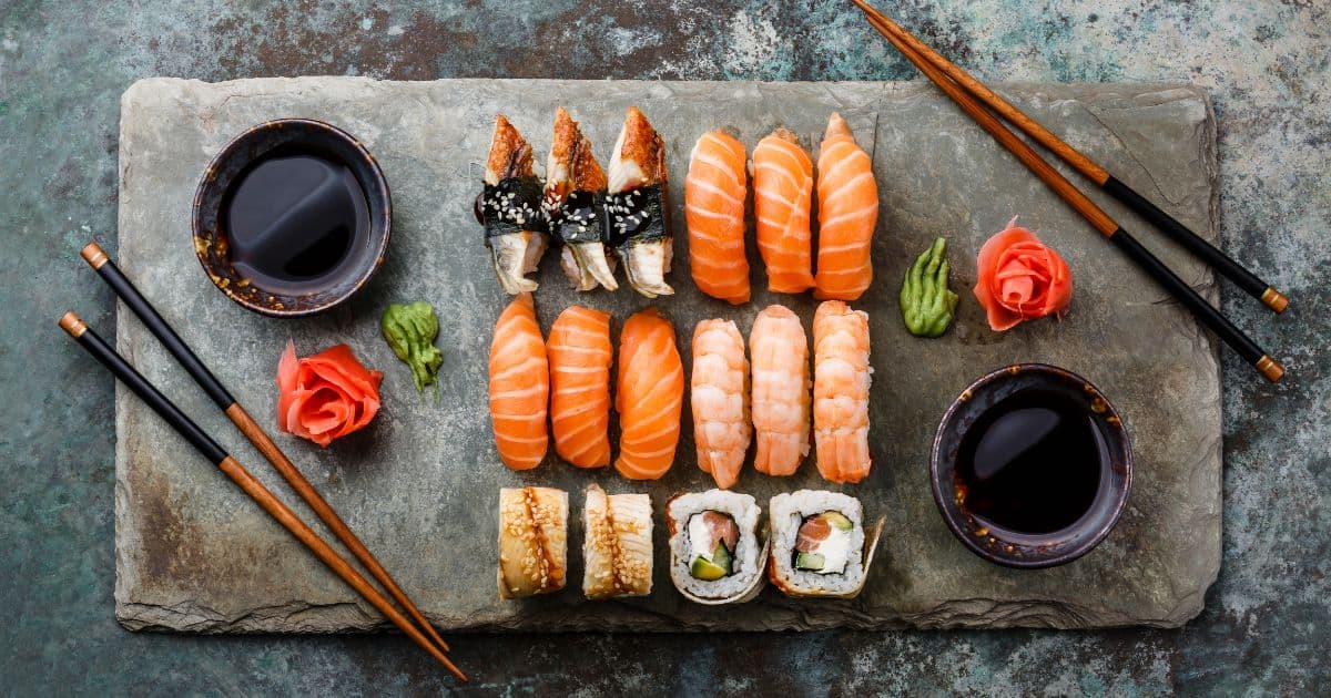 Platter with a variety of sushi rolls, chop sticks, and a sauce dish