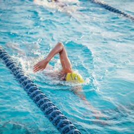 Person doing freestyle stroke in a swimming pool lane