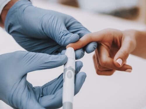 Image of doctor pricking a patient's finger with a pen.