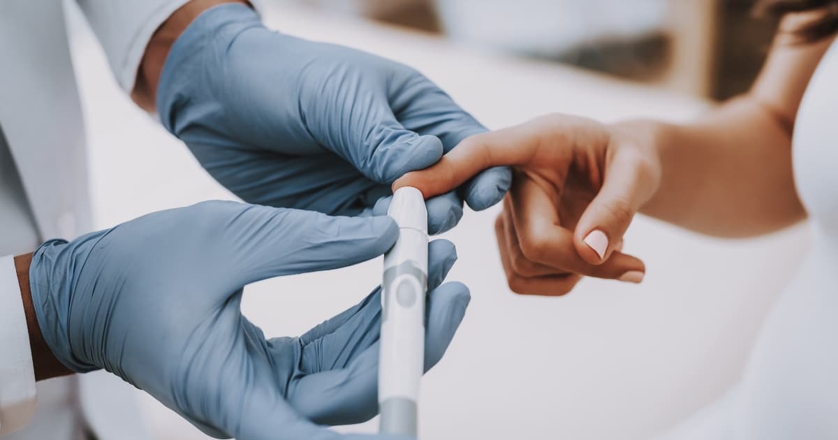 Image of doctor pricking a patient's finger with a pen.