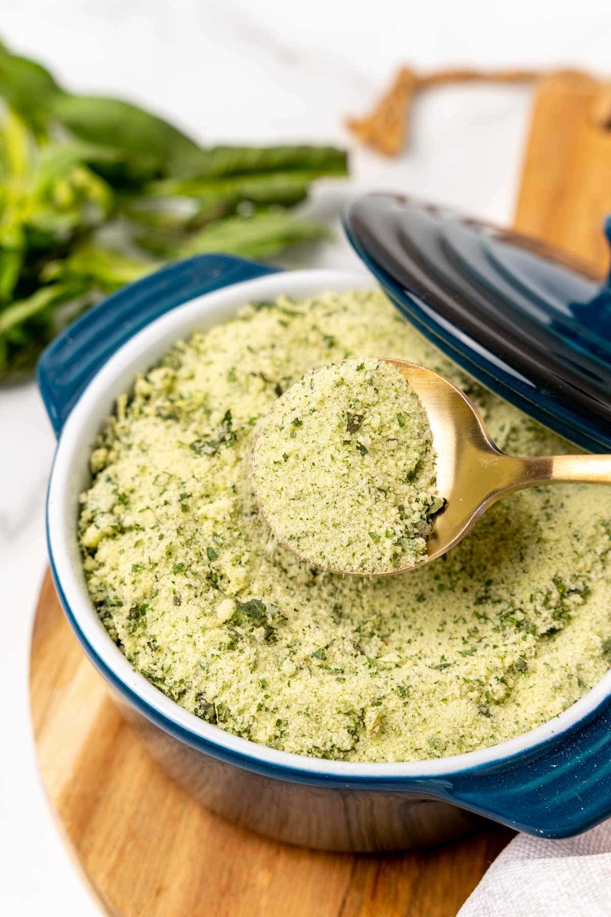 Spoonful of basil salt held over a pot of salt