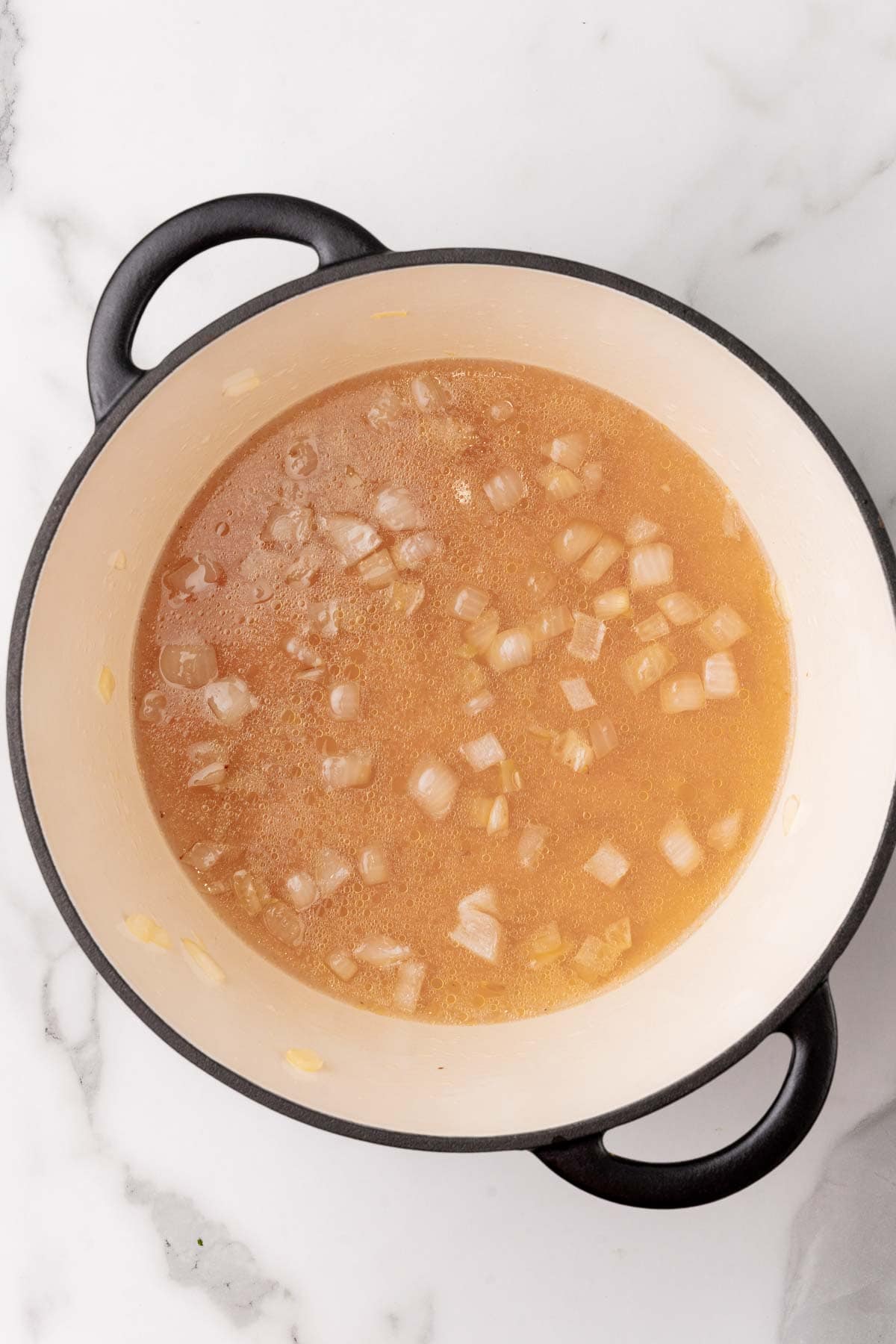 Broth and onions simmering in a pot