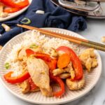 Chicken cashew stir-fry on a plate with rice and chopsticks