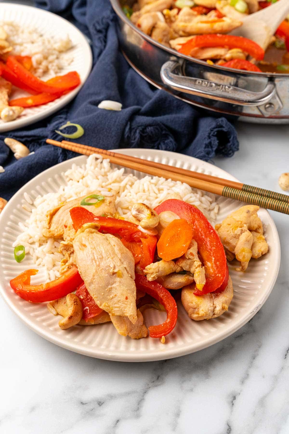 Chicken cashew stir-fry on a plate with rice and chopsticks
