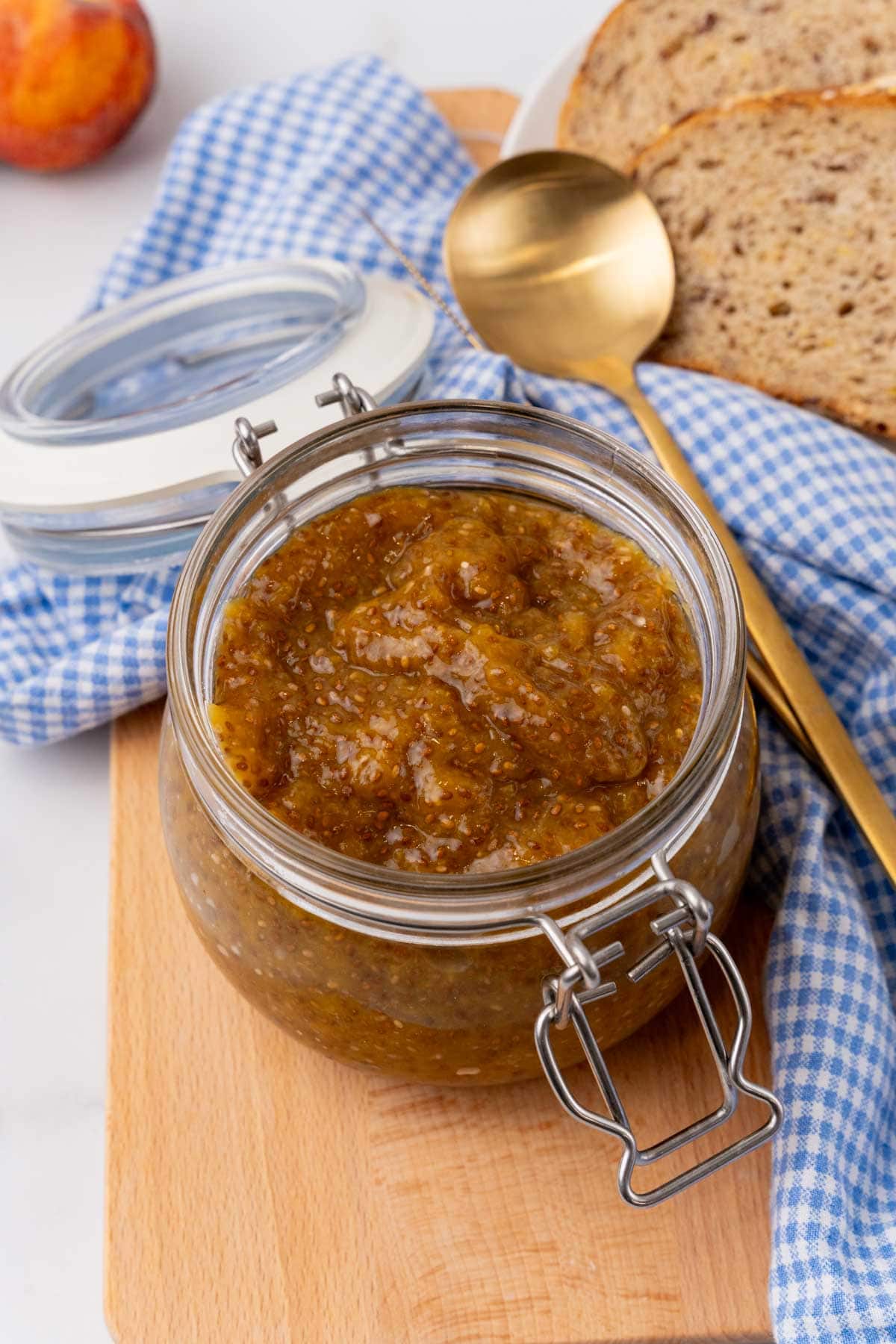 Open jar of peach chia jam with a spoon