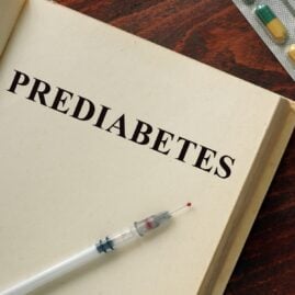 Prediabetes written in a book with various medications spread on a table