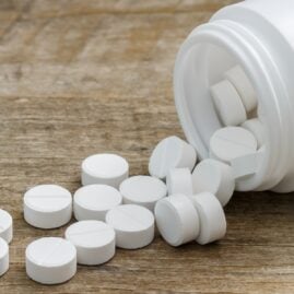 Metformin pills spilling out of a bottle onto a table